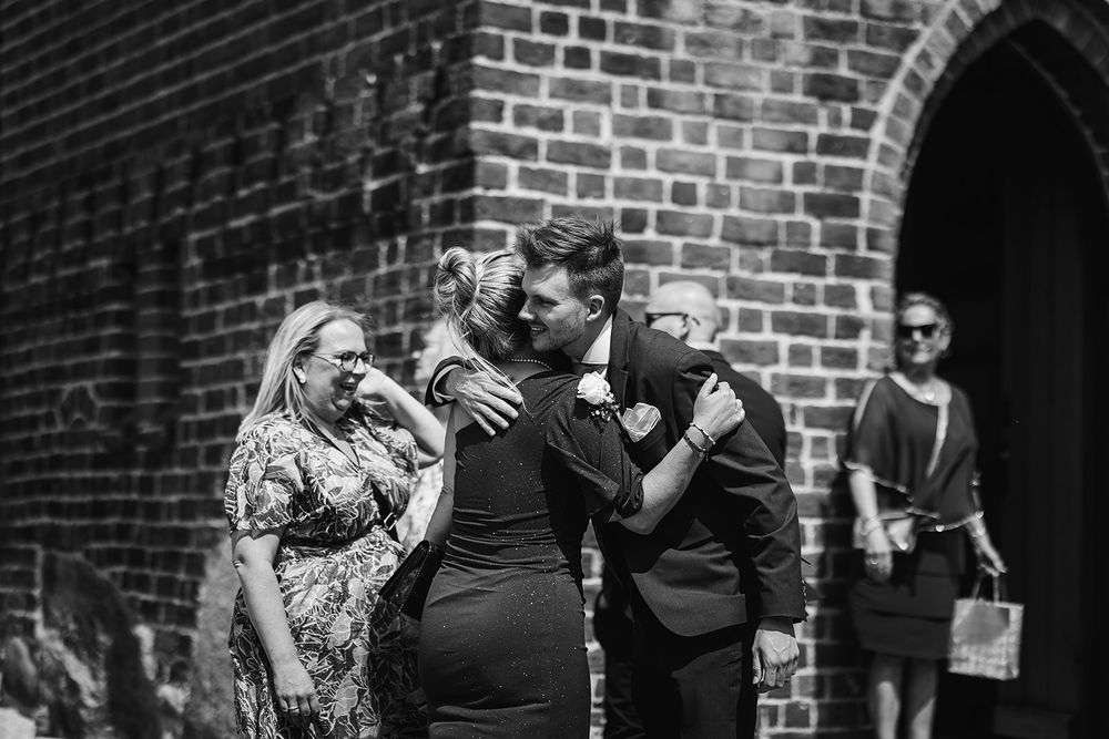 Guests dancing and celebrating at an outdoor wedding reception near a brick church building.