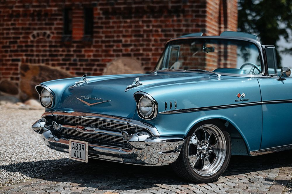 A classic blue 1957 Chevrolet Thunderbird convertible car shown from multiple angles on a cobblestone surface.