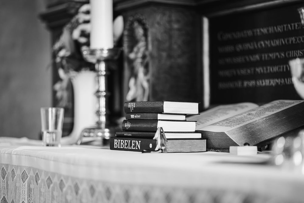 Black and white close-up of books arranged on wooden shelves in a library or study room.