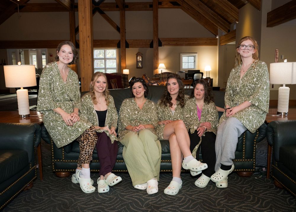 A group of people sitting together in a cozy indoor setting wearing casual clothing and white socks.