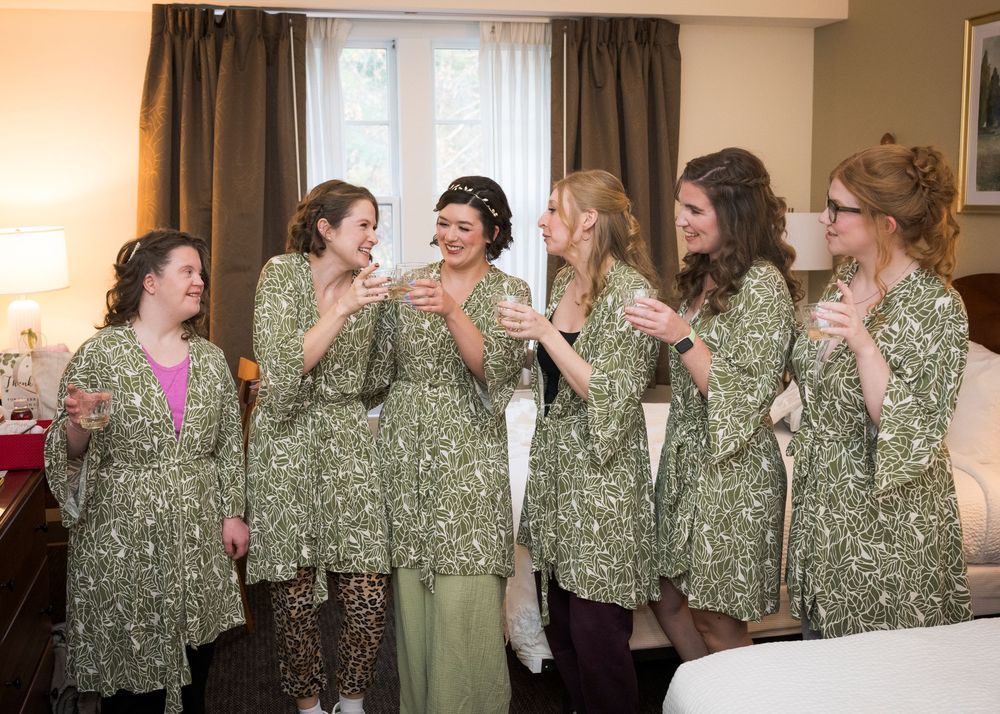 A group of women wearing matching green floral robes share a candid moment together in a room.