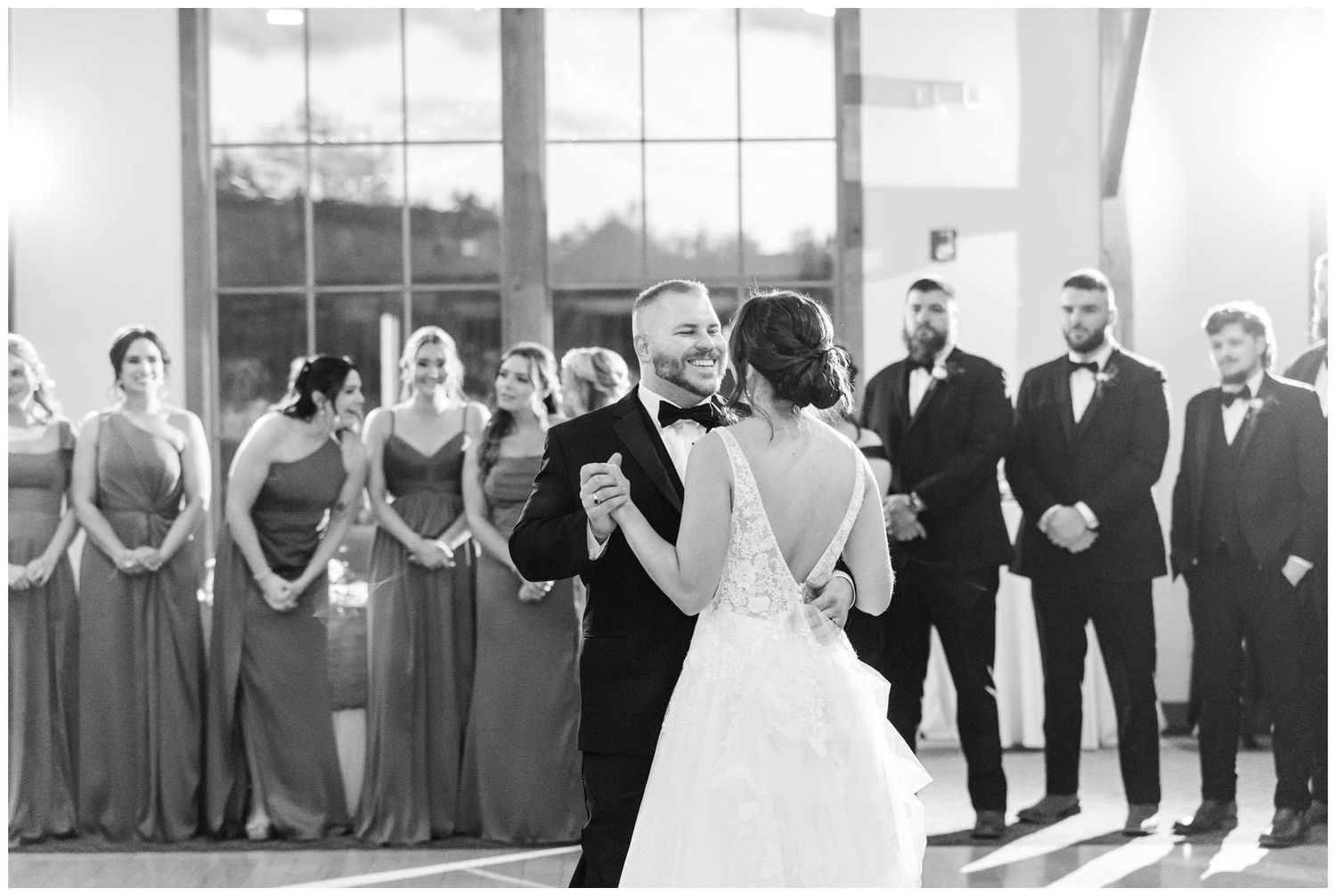 A black and white wedding party lineup poses together in formal attire during a celebration event.