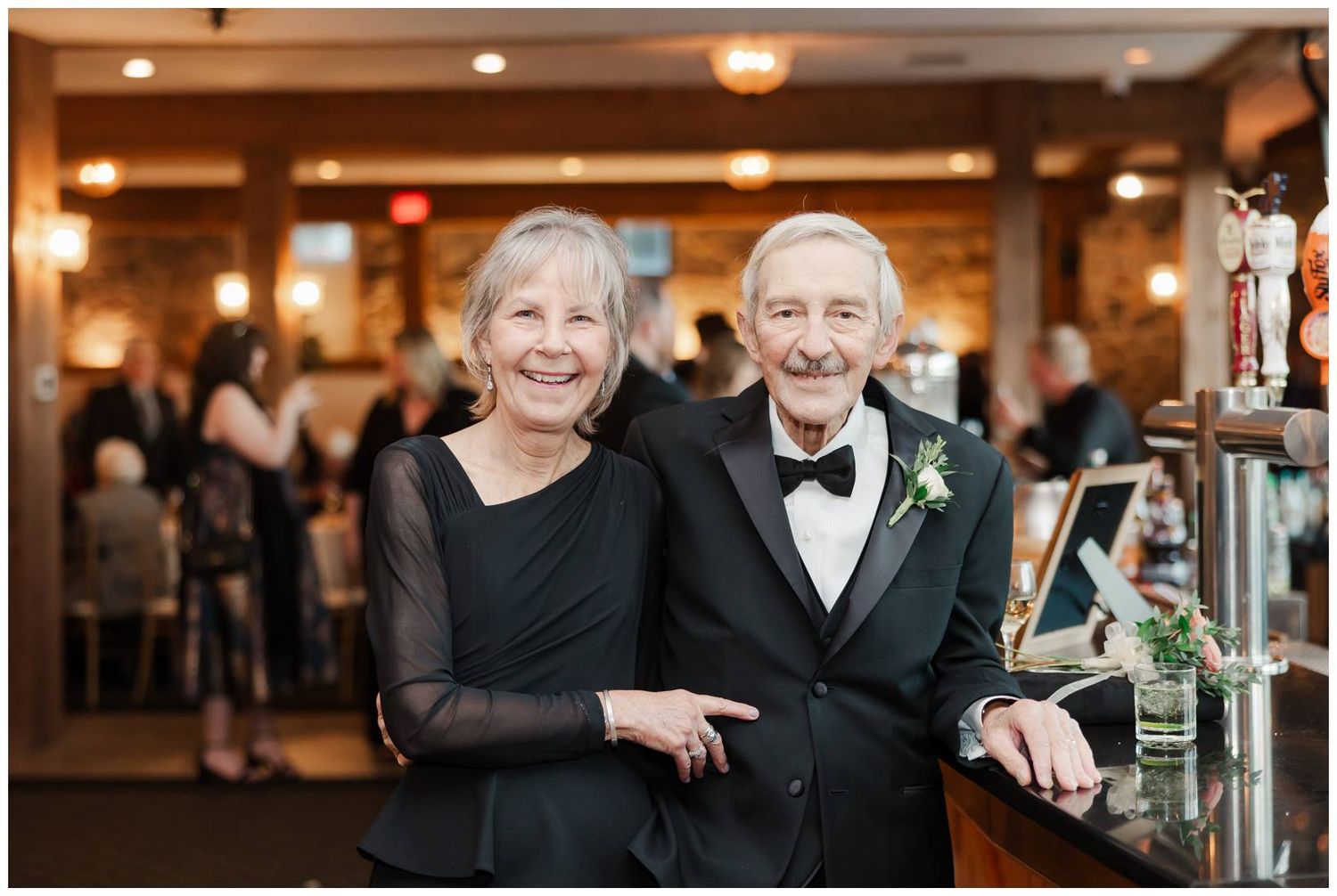 Wedding guests and couples dancing and celebrating together on a dance floor at an elegant indoor reception venue.