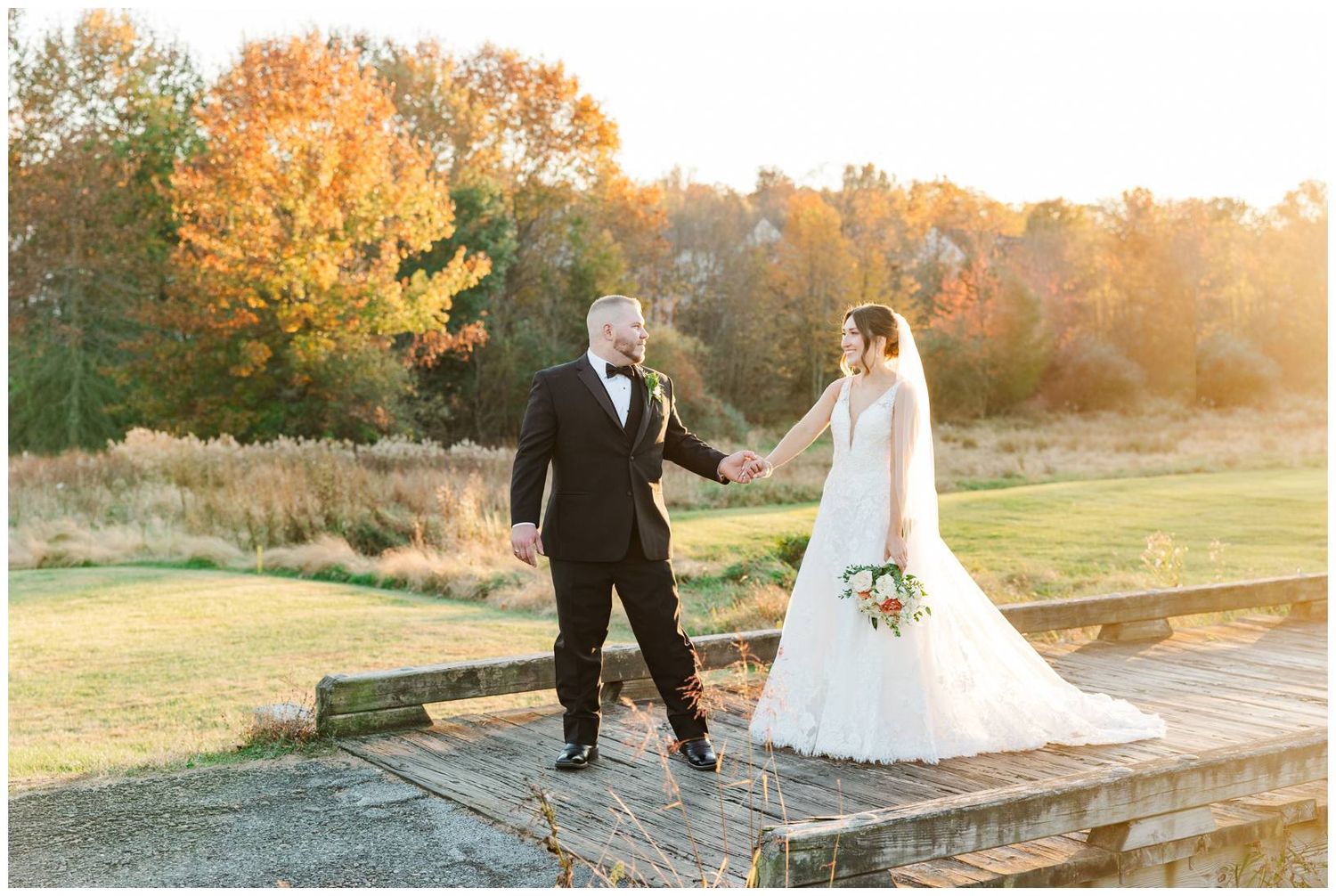 Wedding couple poses on stone steps surrounded by autumn foliage during golden hour sunset.