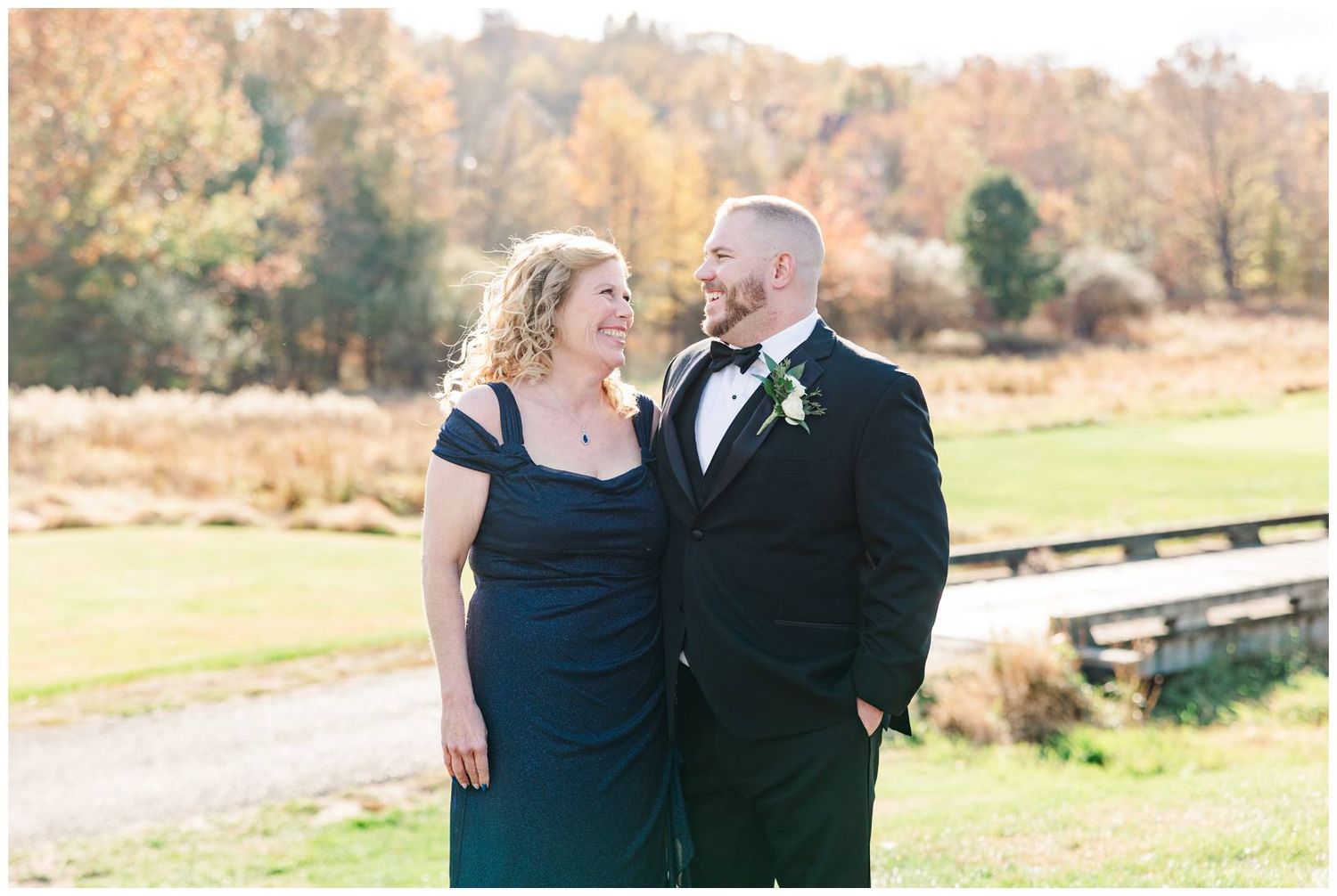 A couple in formal attire shares a romantic moment together during an autumn outdoor photoshoot.