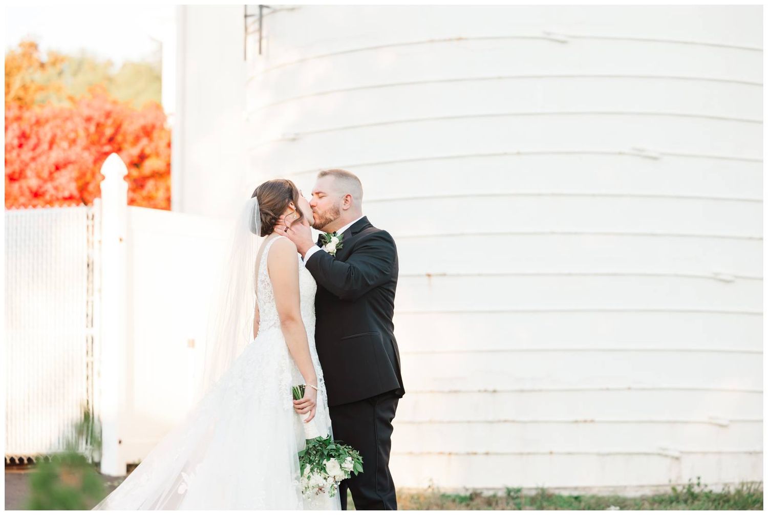 Elegant wedding portraits captured against a rustic white barn backdrop during golden hour.
