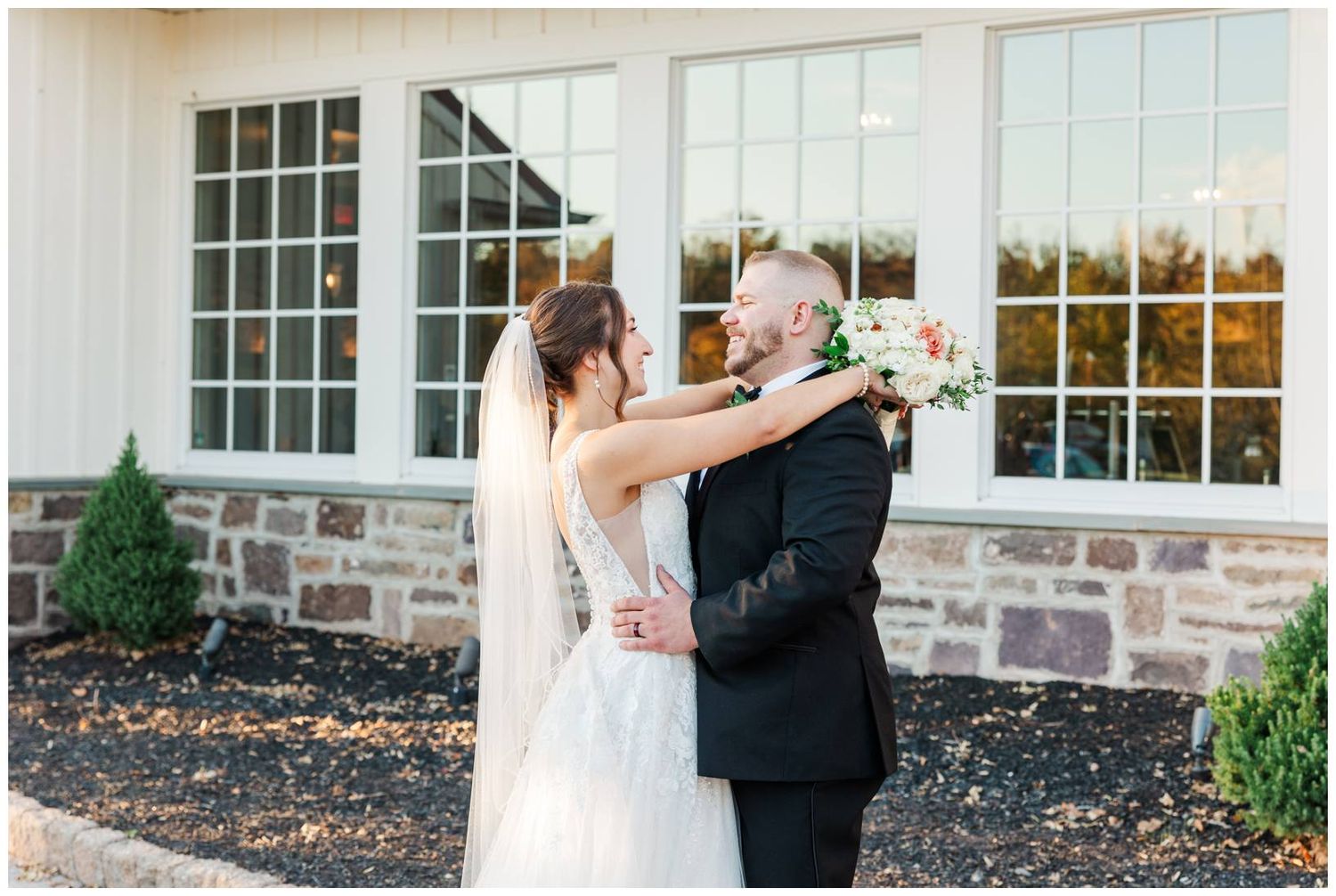 Romantic outdoor wedding couple portraits in front of a white building with large windows.