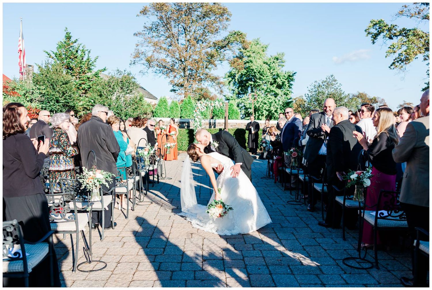 Panoramic view of outdoor wedding ceremony with guests seated on both sides of a stone pathway.