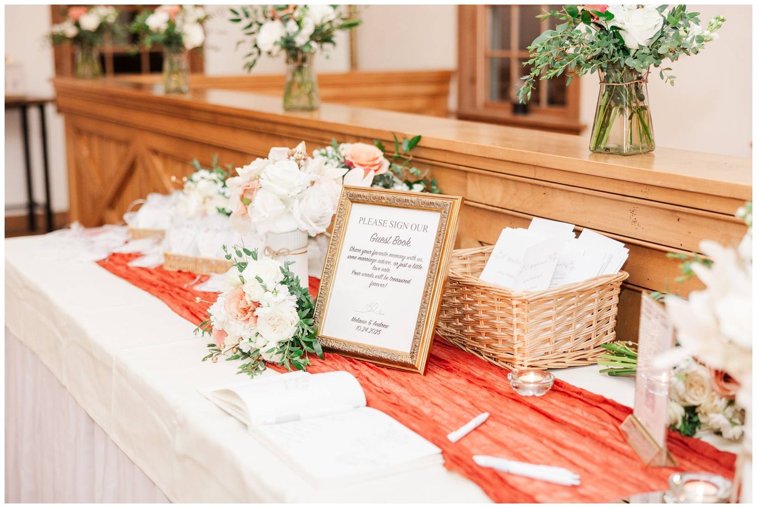 Wedding reception decor featuring white floral centerpieces and greenery on tables with coral accents.