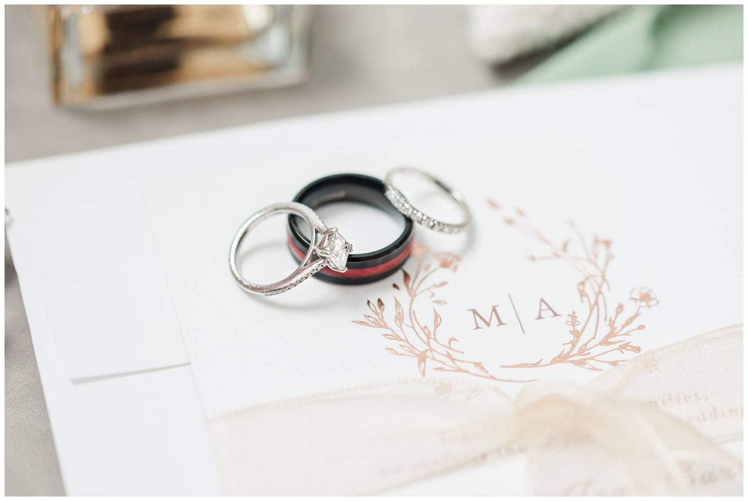 Wedding rings and elegant stationery with delicate rose gold monogram details on white paper.