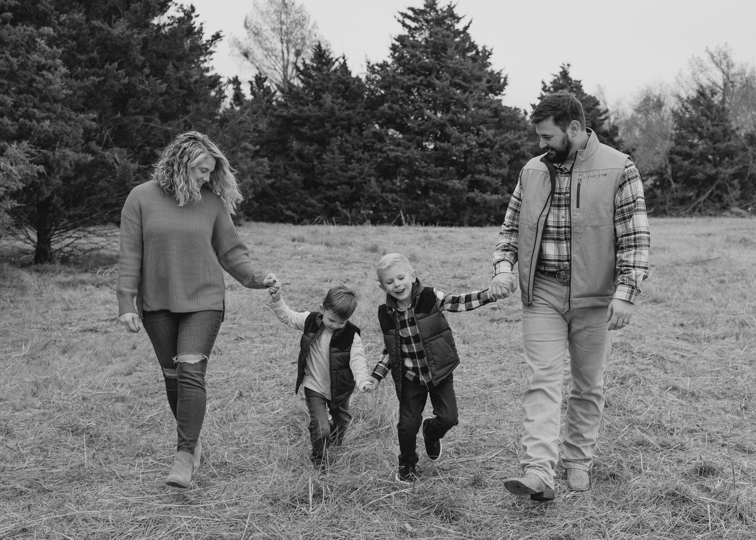 True West Photography - Casual family portrait on blanket during golden hour in rustic field setting.