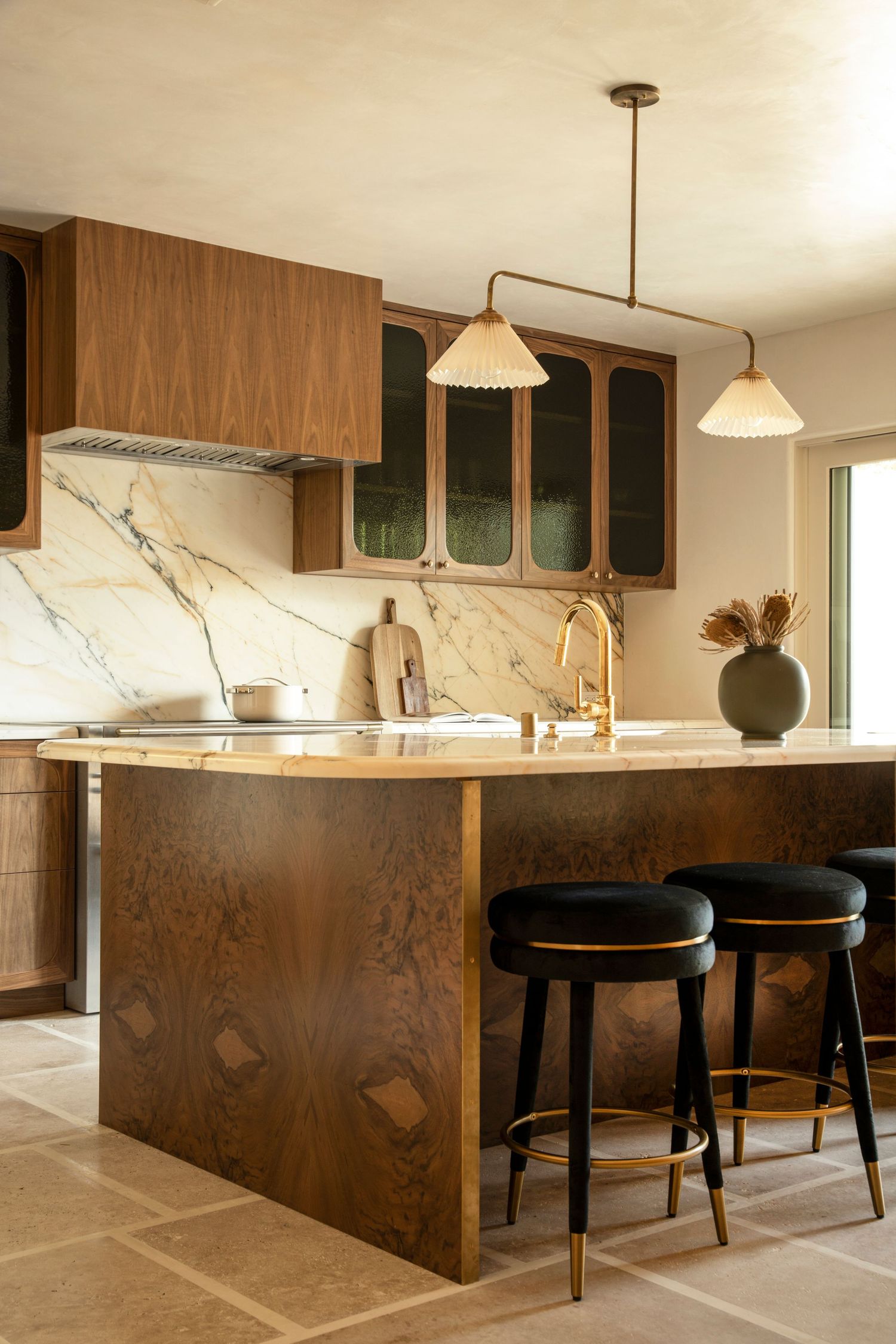Modern kitchen interior with dark wood base cabinets, marble countertops, and pendant lighting.