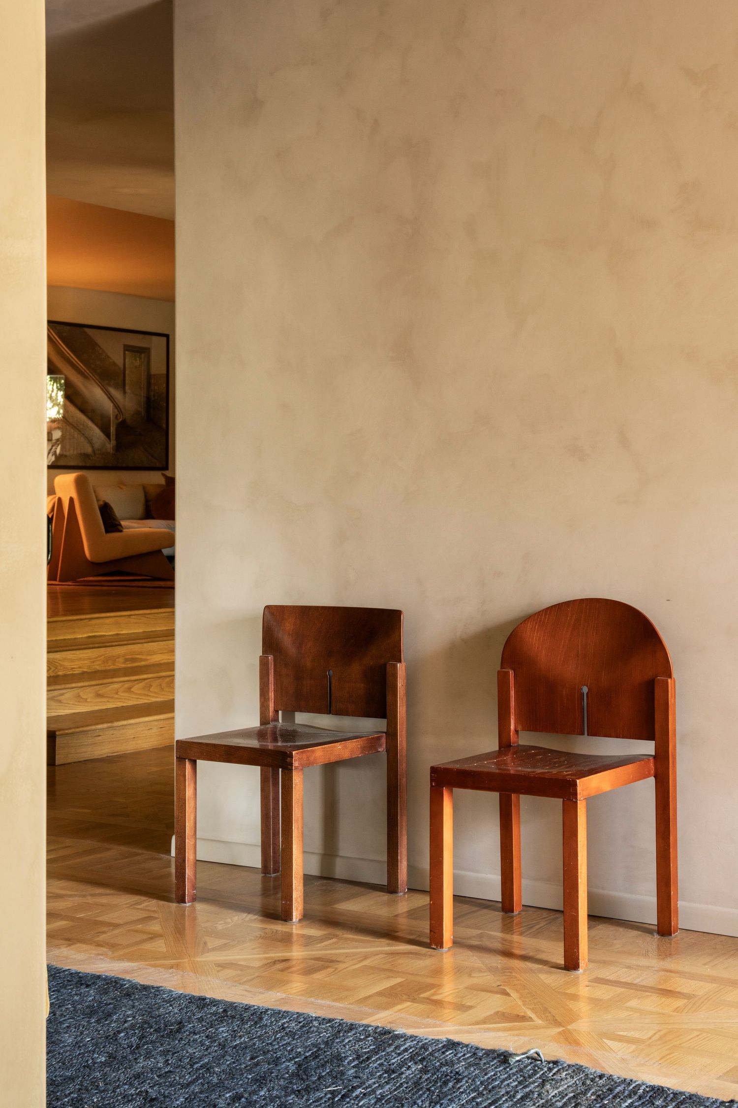 Wooden chairs arranged in a minimalist interior space with cream walls and polished floors.