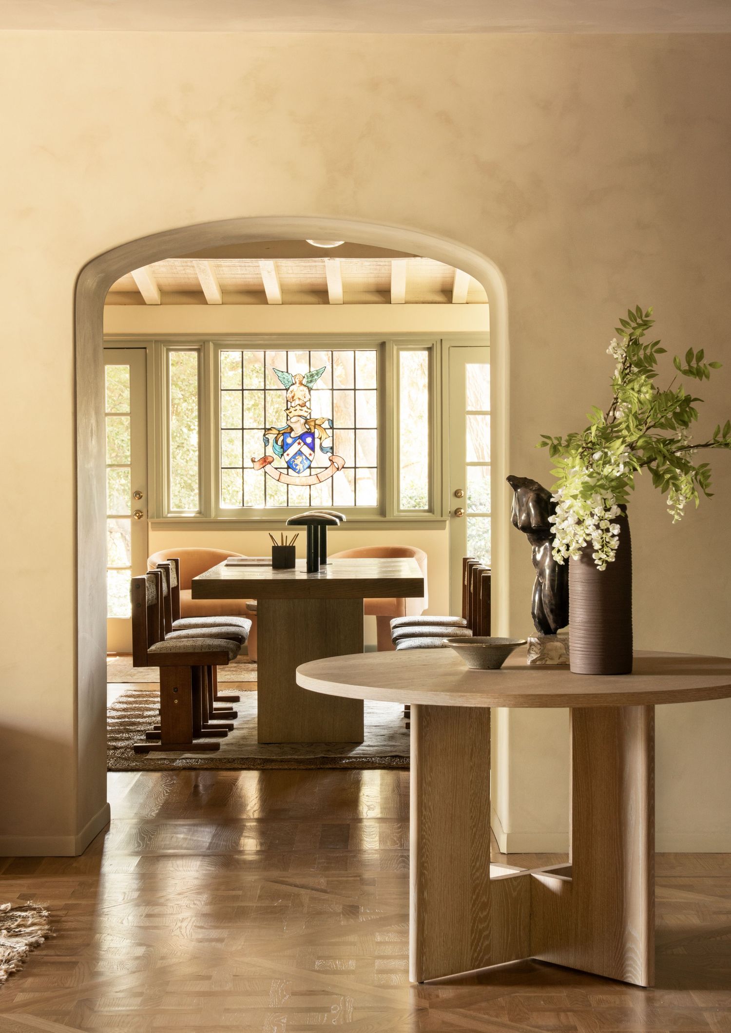 Modern minimalist interior space with wooden floors, white walls, and built-in seating areas near large windows.
