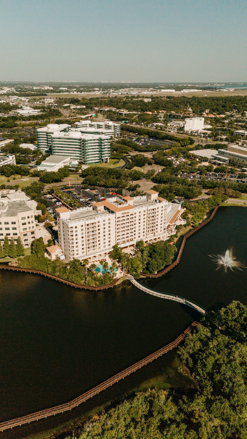 Aerial panoramic view of waterfront buildings and wooden boardwalk along coastal inlet in Florida.