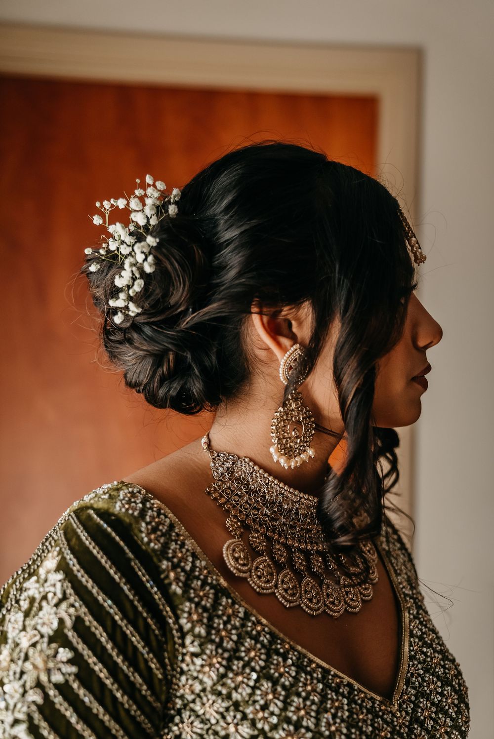 Side profile views showing intricate bridal jewelry and white floral hair accessories against warm lighting.