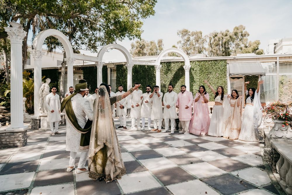 A wedding party stands together in an outdoor courtyard venue with elegant white and neutral decor.