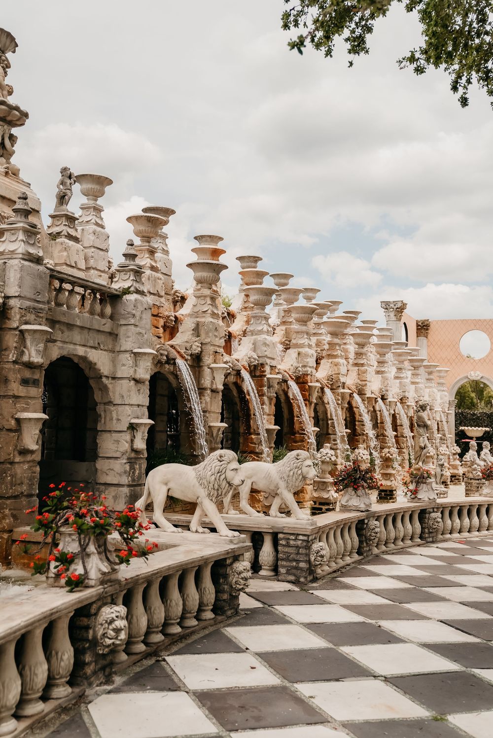 Ornate stone balustrade with lion statues and decorative columns creating a grand architectural walkway with checkerboard floor.
