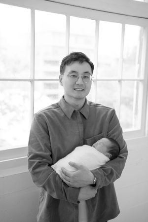 A series of four similar black and white photos showing someone in a gray jacket holding a small bundle.