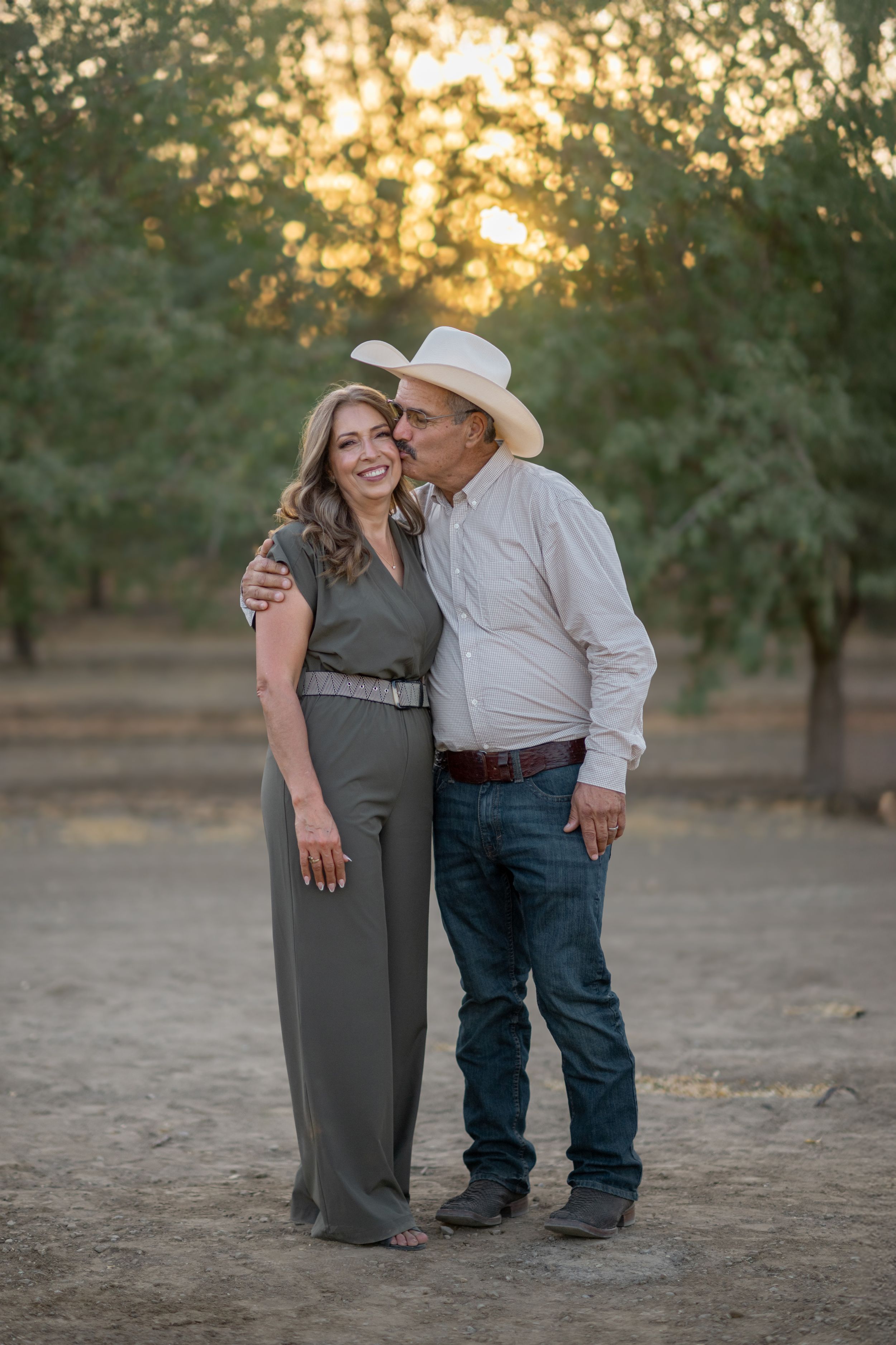 A couple shares an intimate moment while standing together at golden hour in a natural outdoor setting.