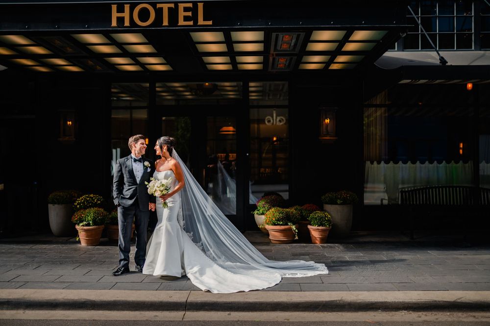 Elegant wedding photos captured outside a hotel entrance at night with dramatic lighting.