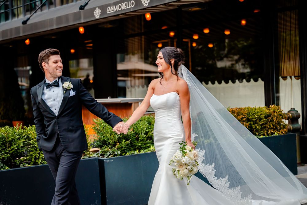 Bride and groom laughing together during their wedding photo session in an urban setting.