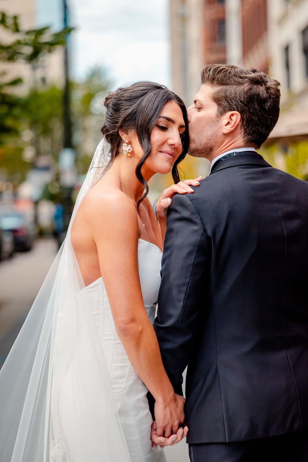 A bride and groom share a romantic kiss sequence outdoors on their wedding day.