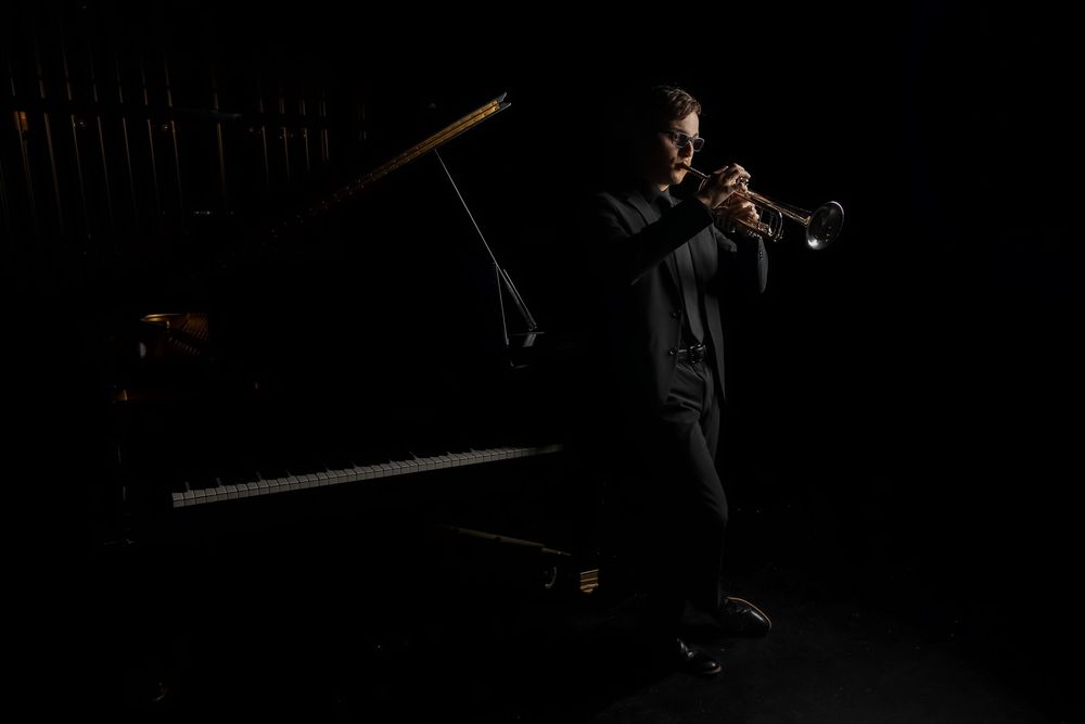 A silhouetted figure performs on stage in dramatic lighting during a theatrical performance.