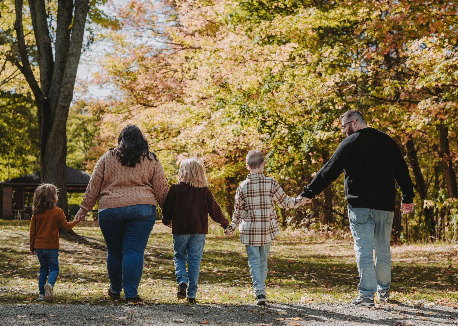 Group of people walking together on an autumn path with colorful fall foliage in the background.