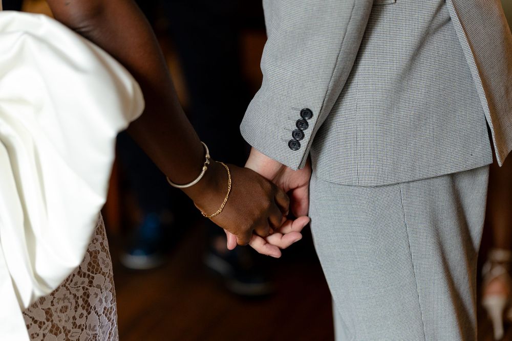 Close-up shot of a couple holding hands with wedding attire visible.