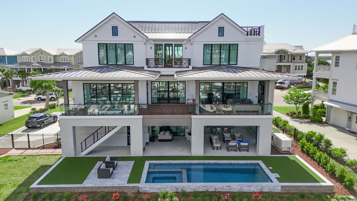 Modern luxury three-story white house with swimming pool and manicured lawn.