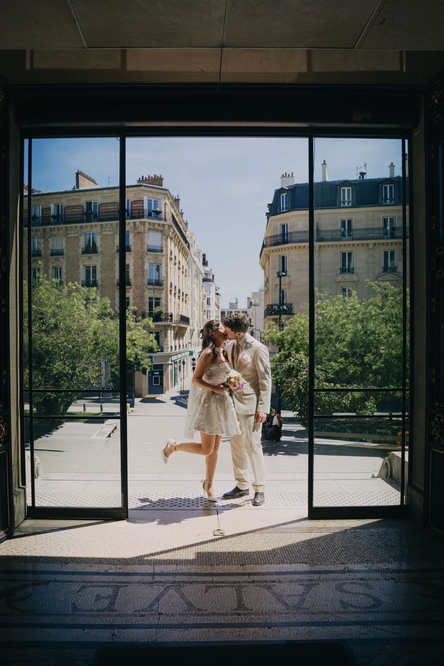 Image très graphique d'un couple qui s'embrasse dans l'encadrement de la porte de la mairie d'Asnières. Bâtiments Haussmaniens en fond