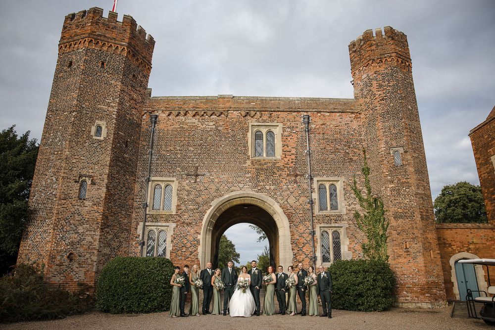 Wedding party portrait in front of medieval castle-style architecture with stone towers.