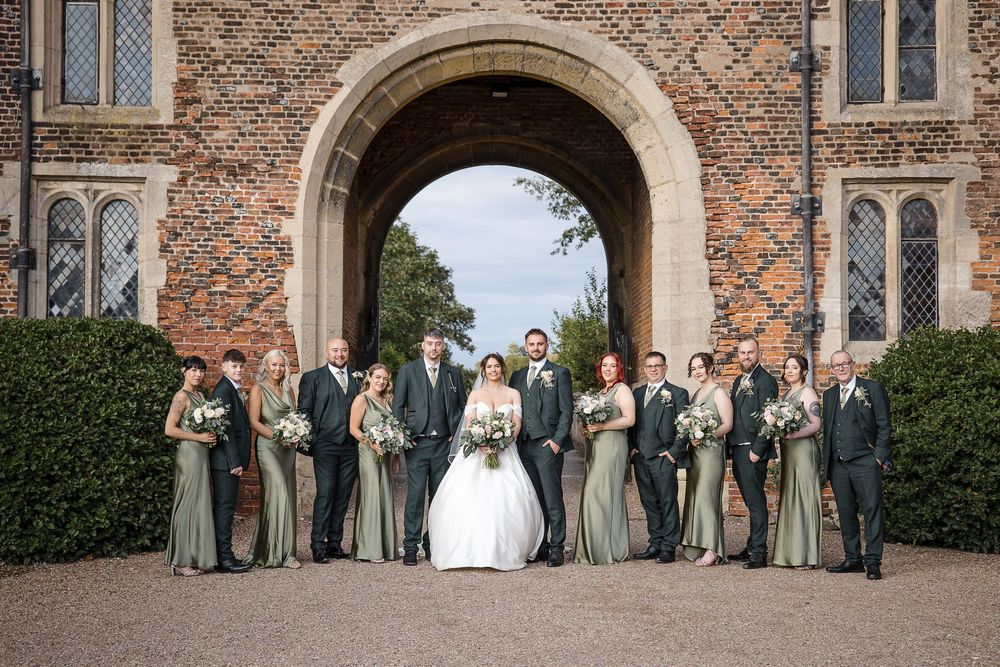 Wedding party poses in front of historic brick church building on sunny day.