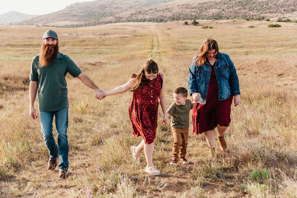 Family walking together through a scenic golden field with mountains in the background.