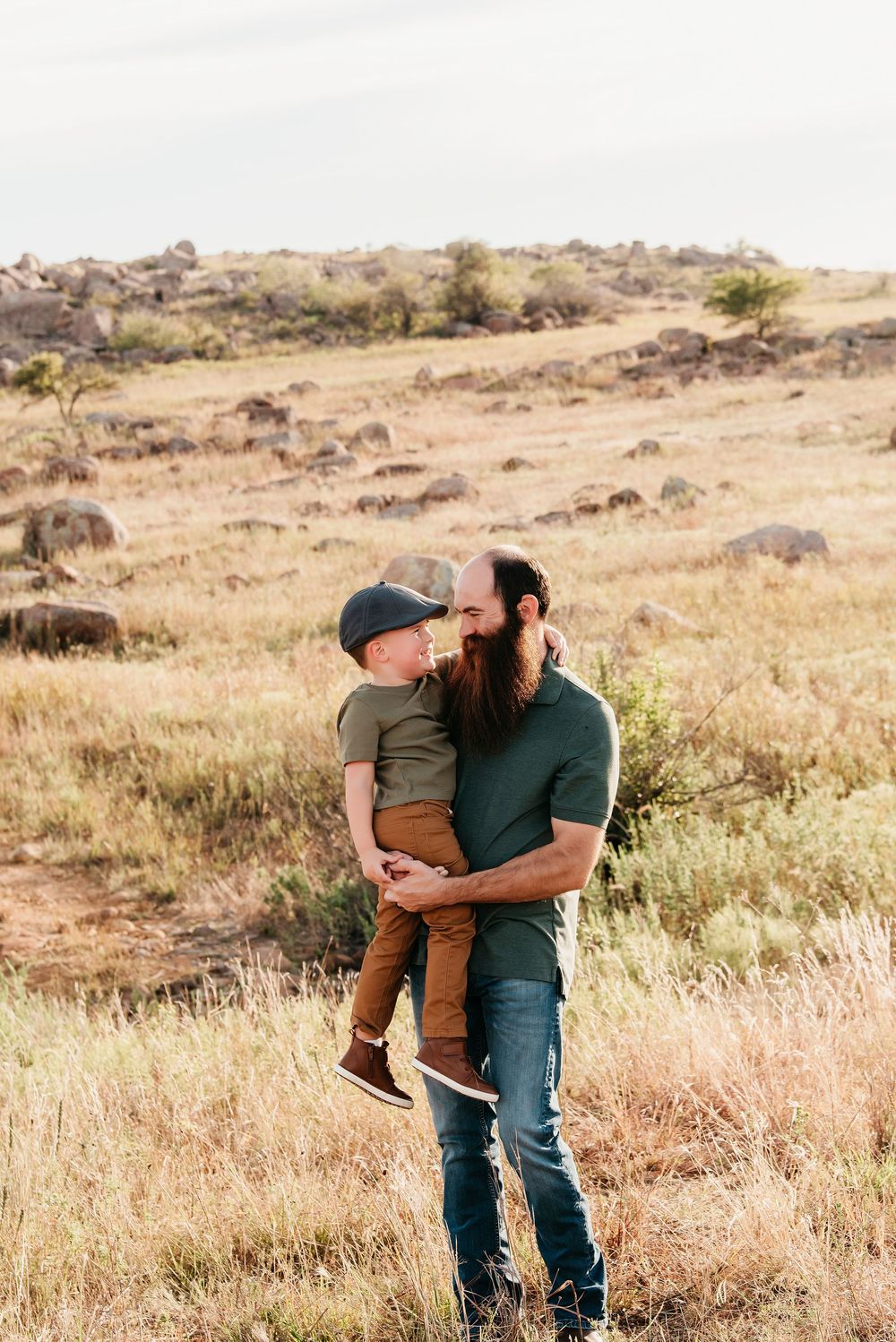 Playful couple sharing intimate moment in rustic outdoor setting with rolling hills.