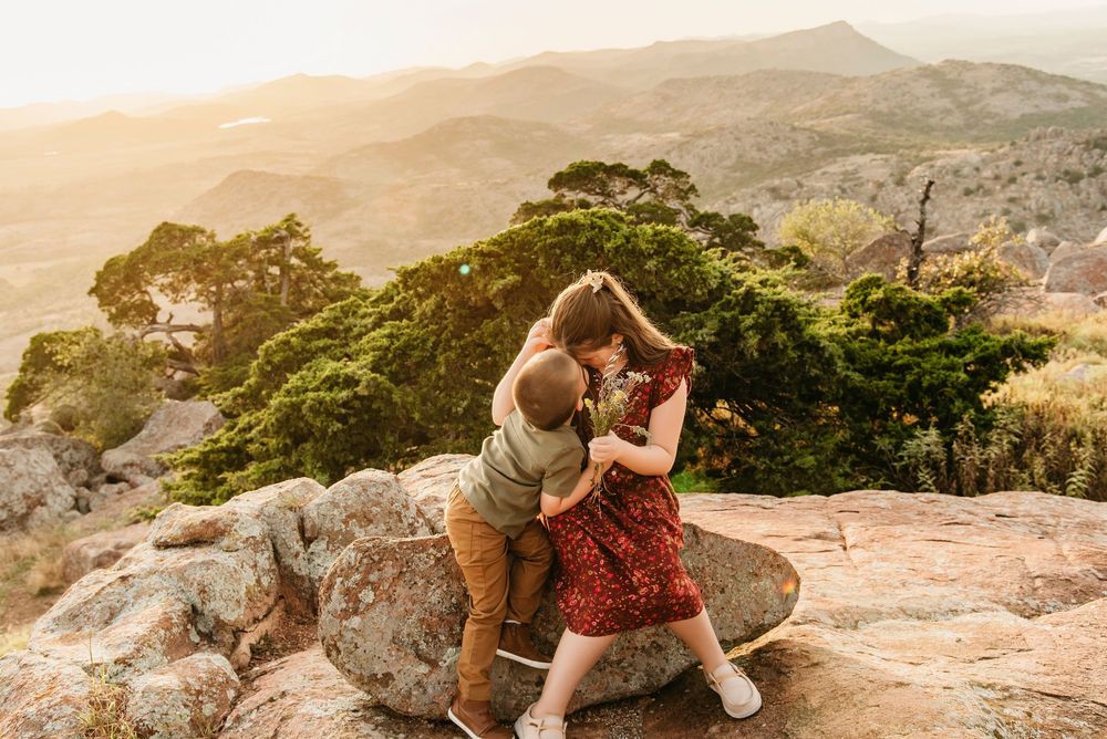 Couple sits together on rocky mountain overlook during golden hour.