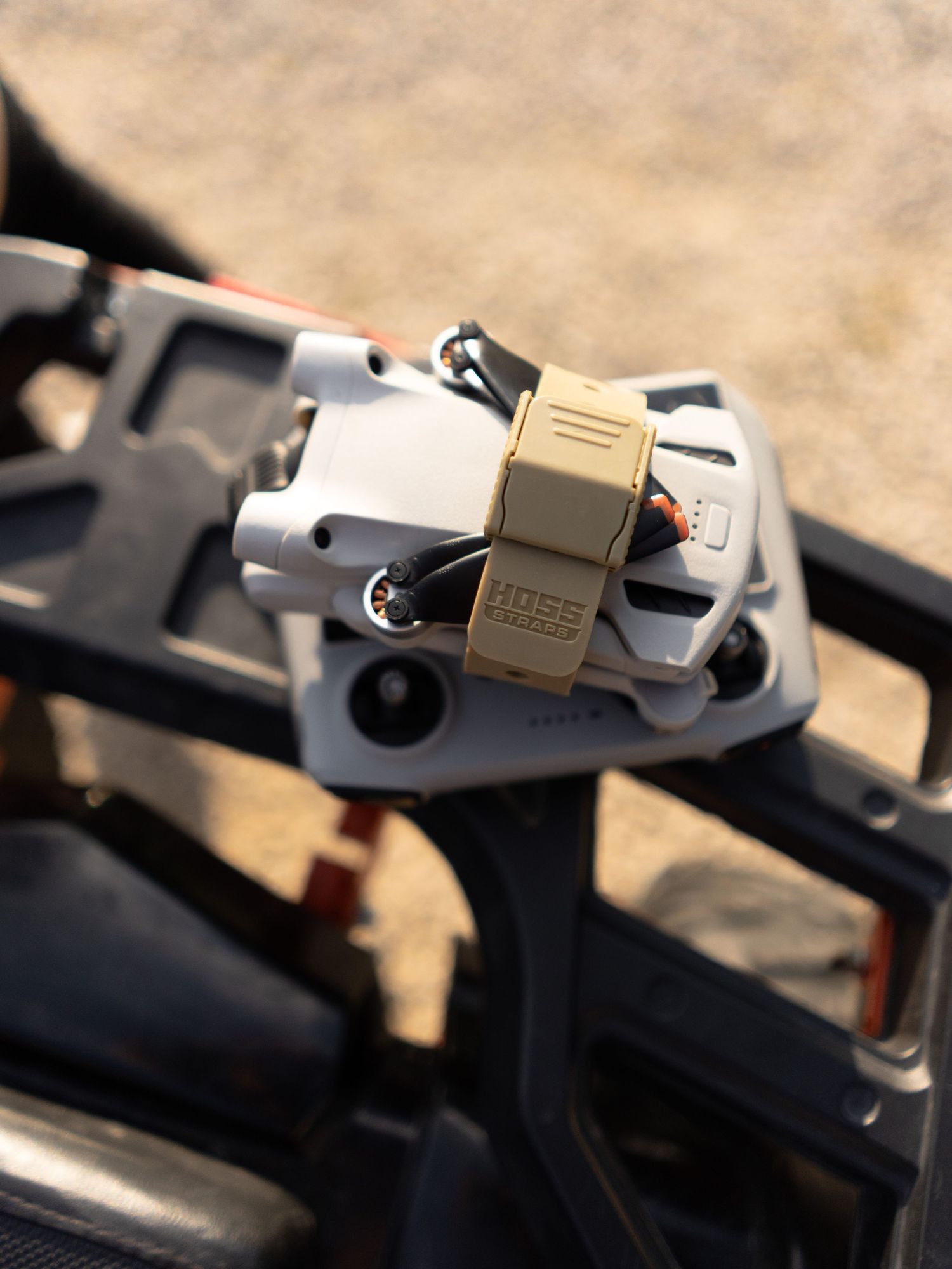 Close-up of metal tactical gear attachments with tan accents in sunlight.