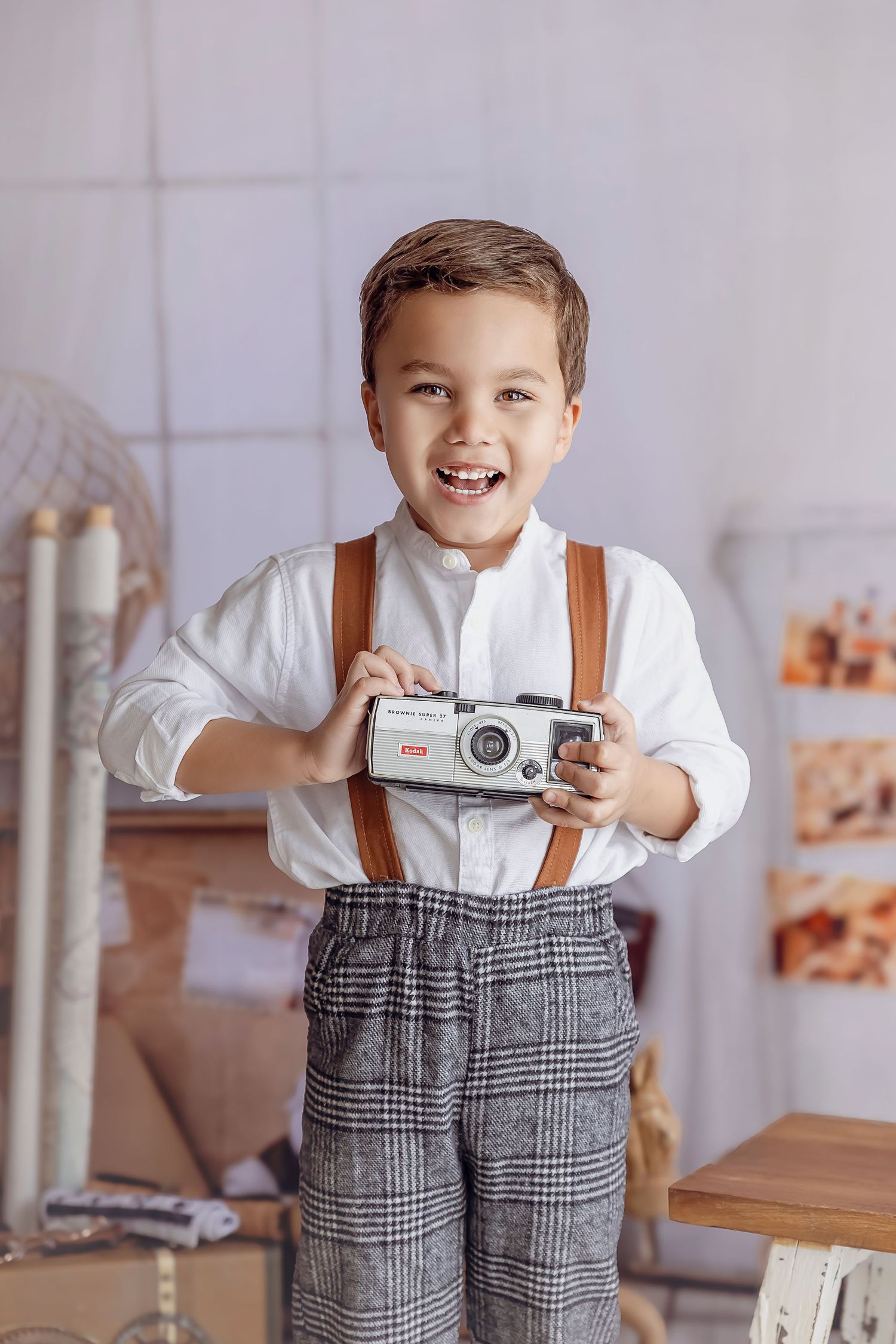 Nino de 5 anos siendo Fotografiado por Detres photography aguanta una camara vintage y sonrie fuerte y grande