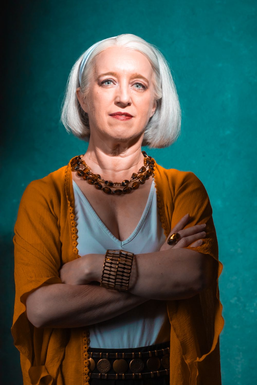 Portrait series against turquoise background showing expressive poses in orange clothing and white hair.