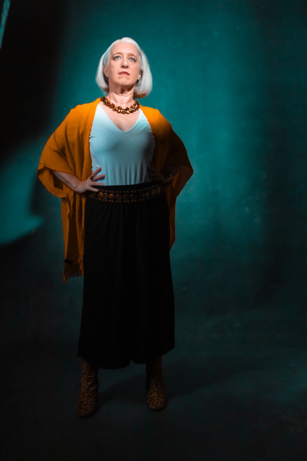 Artistic portrait series showing a person in black and teal clothing against a dramatic teal backdrop.