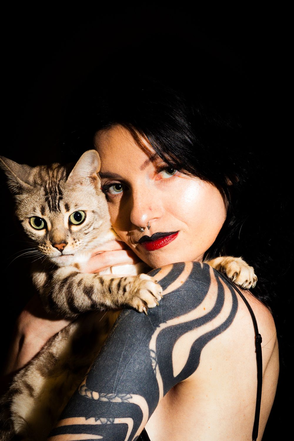 A series of artistic portraits showing a cat resting on someone's shoulder with dark clothing and tribal tattoos.