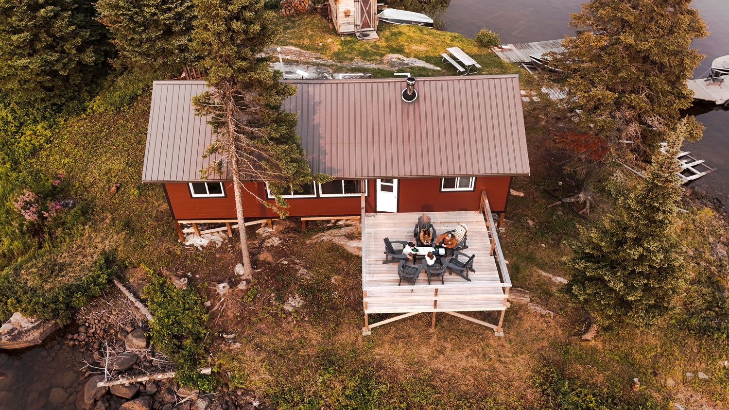 Row of red and white lakeside cottages surrounded by fall foliage.