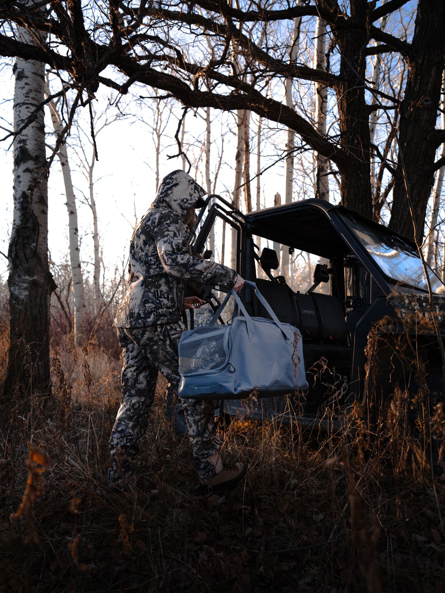 Camouflaged hunting equipment set up in wooded area during late autumn.