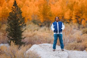 Person standing on rock with vibrant orange fall foliage behind them.