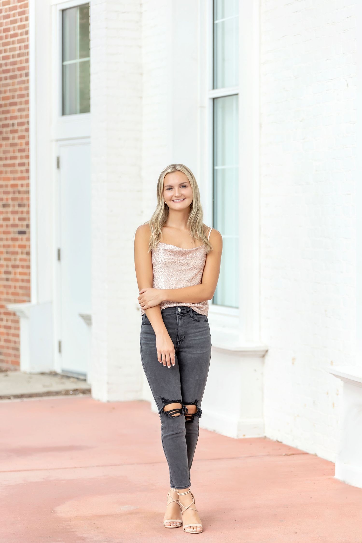 Mason City High School Senior girl in ripped jeans and sandals posing in front of the Library.
