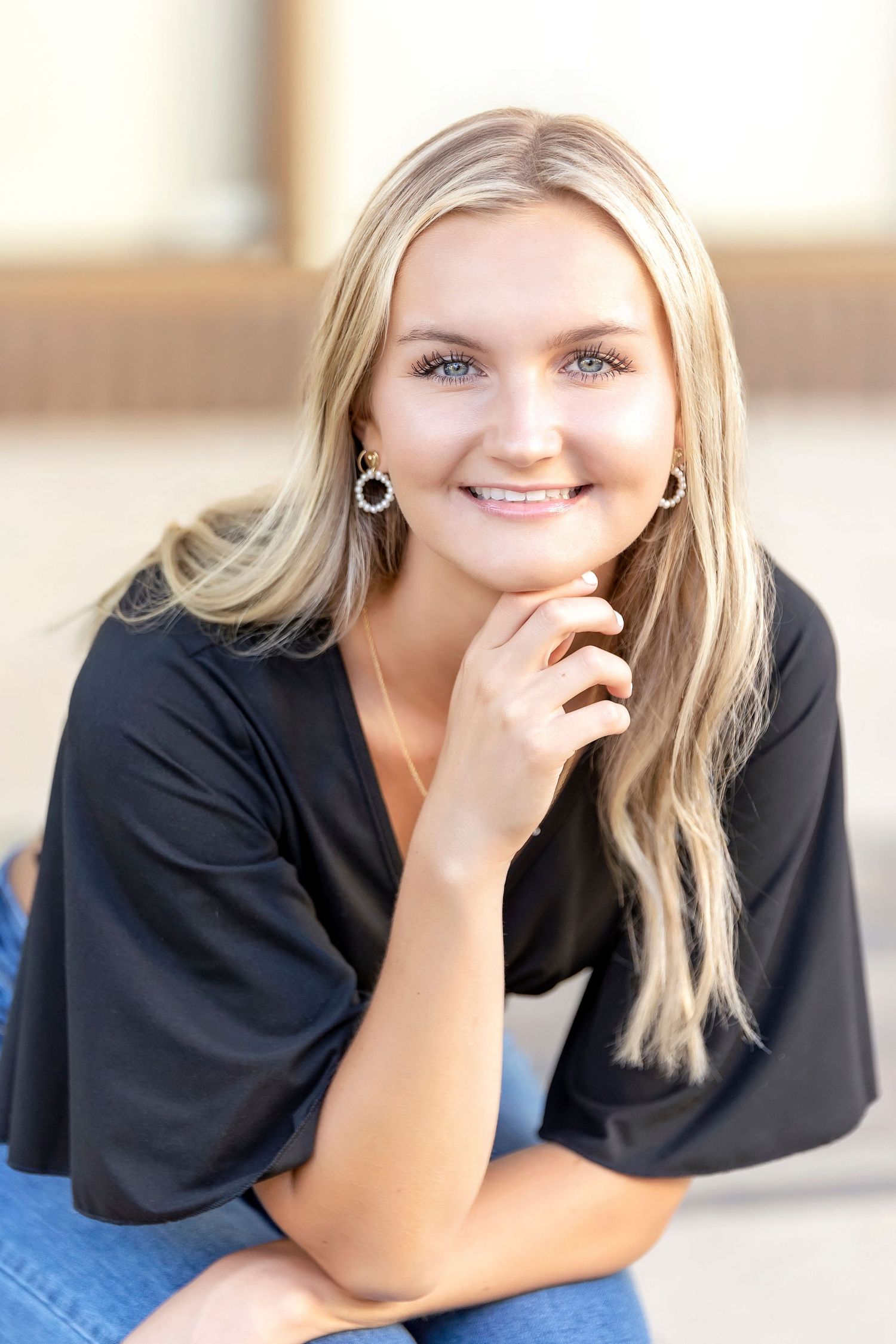 Mason City High School Senior portraits against brick wall with pink flowers foreground in Mason City senior session