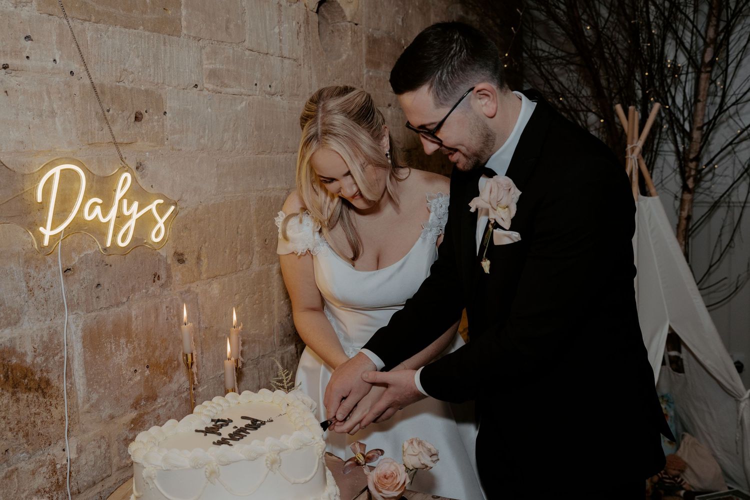 Wedding guests celebrate during a reception in a rustic brick venue with lattice wall decor and greenery.