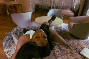 Person lying on patterned rug in living room with modern furniture.