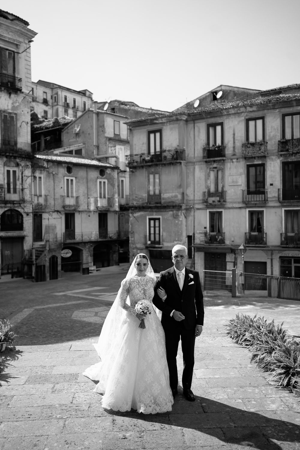 A sequence of wedding photos showing a couple walking through a charming Italian village square.
